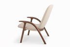 Seitenansicht des ALPHA Loungesessels von GoEs mit geschwungenen Armlehnen aus Holz und hellen Polsterungen
