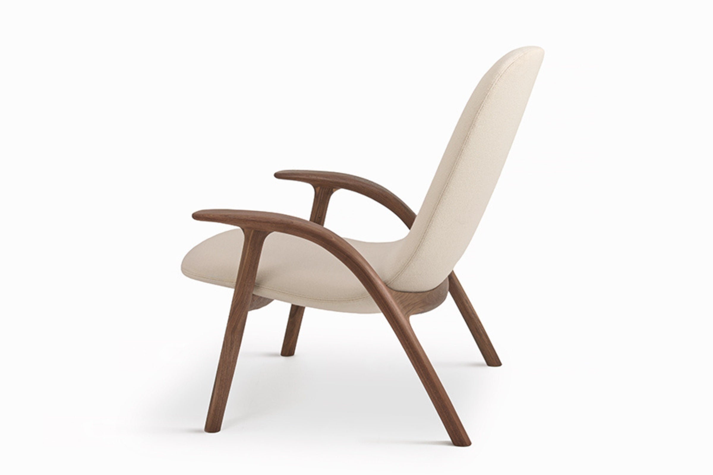 Seitenansicht des ALPHA Loungesessels von GoEs mit geschwungenen Armlehnen aus Holz und hellen Polsterungen