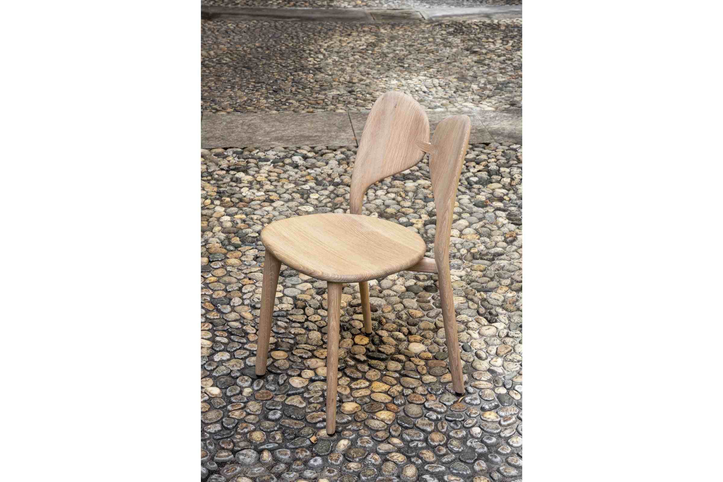 LEPIDA Designer Stuhl von Woak auf einem Kieselsteinboden platziert