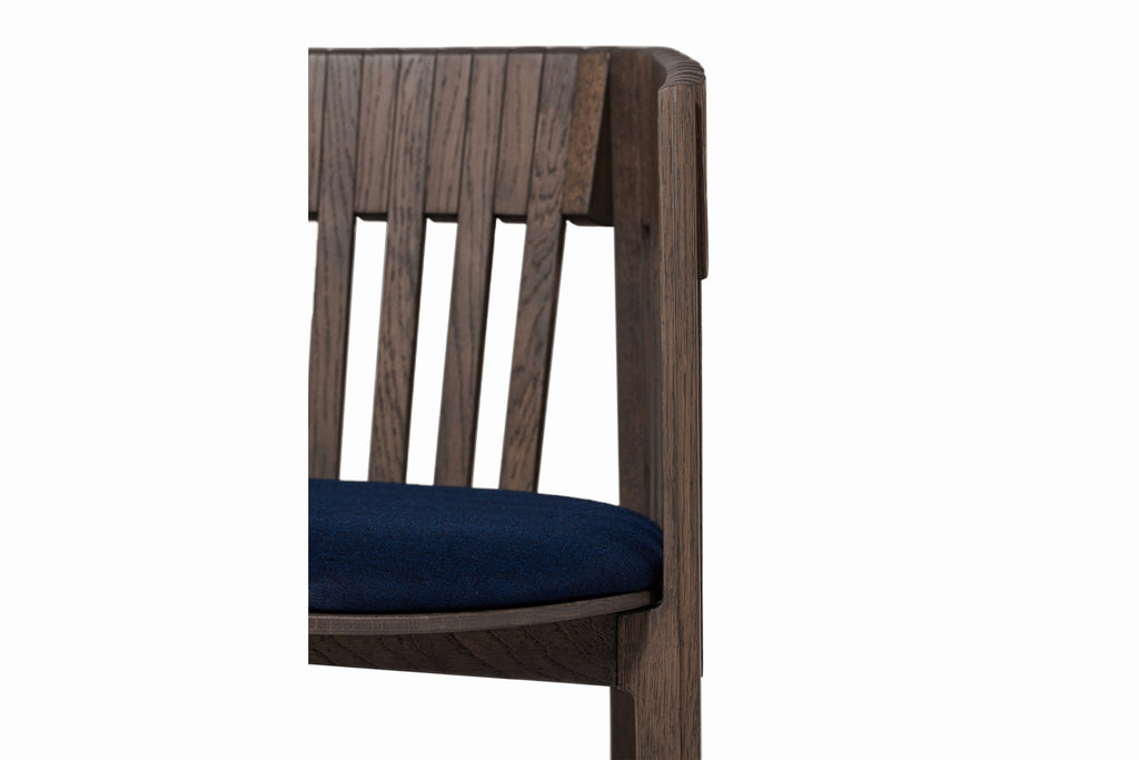 Detailaufnahme des Stuhls mit blauer Sitzfläche und markanter Rücklehne