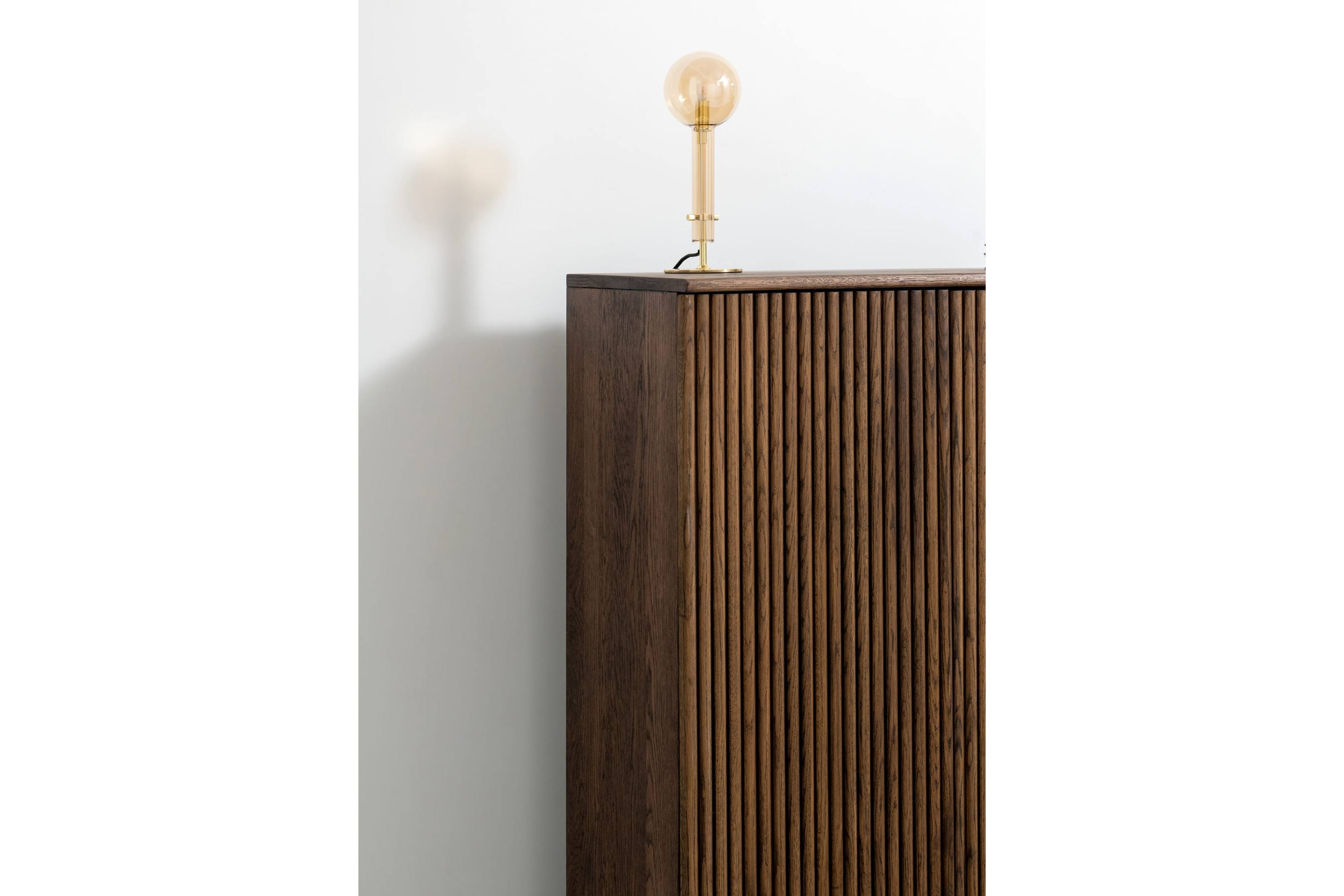 Seitliche Ansicht des GROOVE Highboards aus Massivholz mit dekorativer Lampe