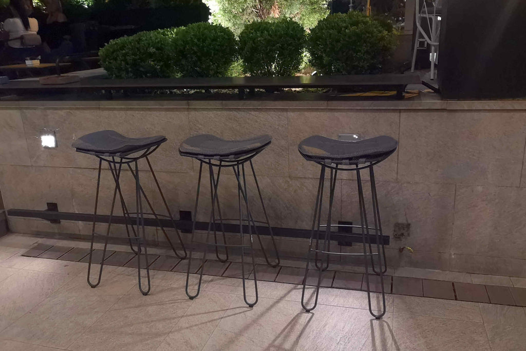 Drei Barhocker bei Nacht an einer Bar im Freien