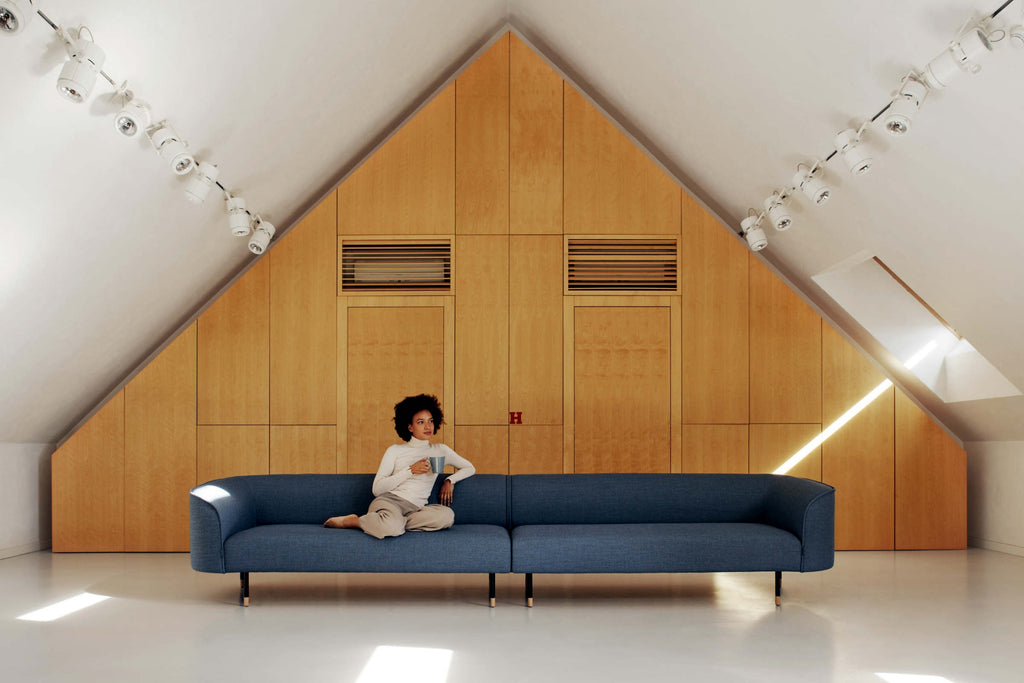 Extralanges blaues Sofa mit einer Person in einem minimalistischen Raum