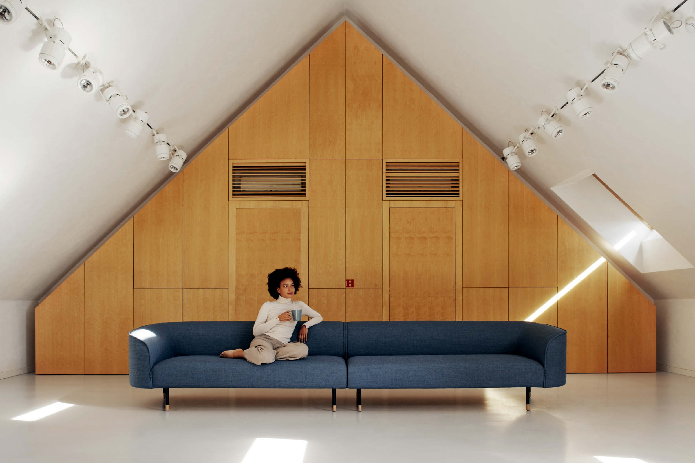 Extralanges blaues Sofa mit einer Person in einem minimalistischen Raum