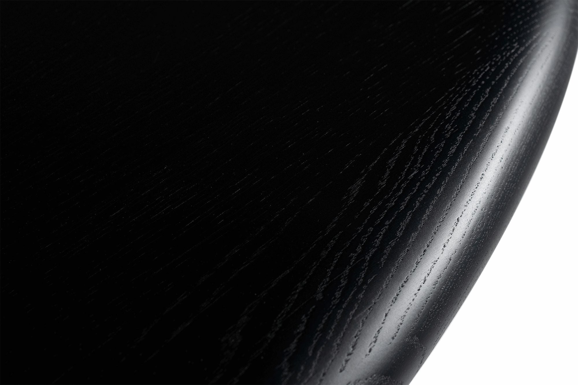 Detailansicht von oben der abgerundeten Kante in Schwarz, die die Holzmaserung hervorhebt