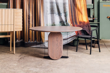 wherry esstisch mit einem gebogenen Tischbein und ein schwarzer Stuhl in einem Raum mit Holzmöbeln und orangefarbenen Vorhängen.